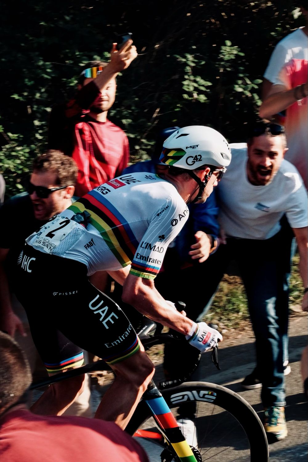 Coureur en maillot arc-en-ciel de champion du monde encouragé par les supporters au bord de la route