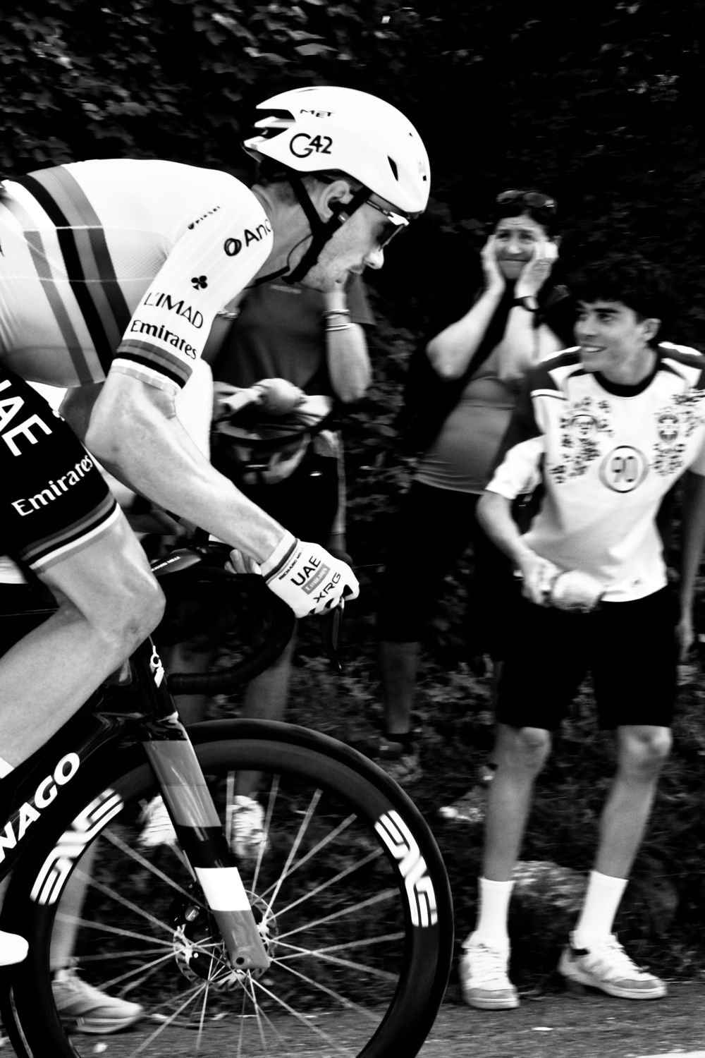 Coureur professionnel en pleine montée devant les spectateurs, en noir et blanc