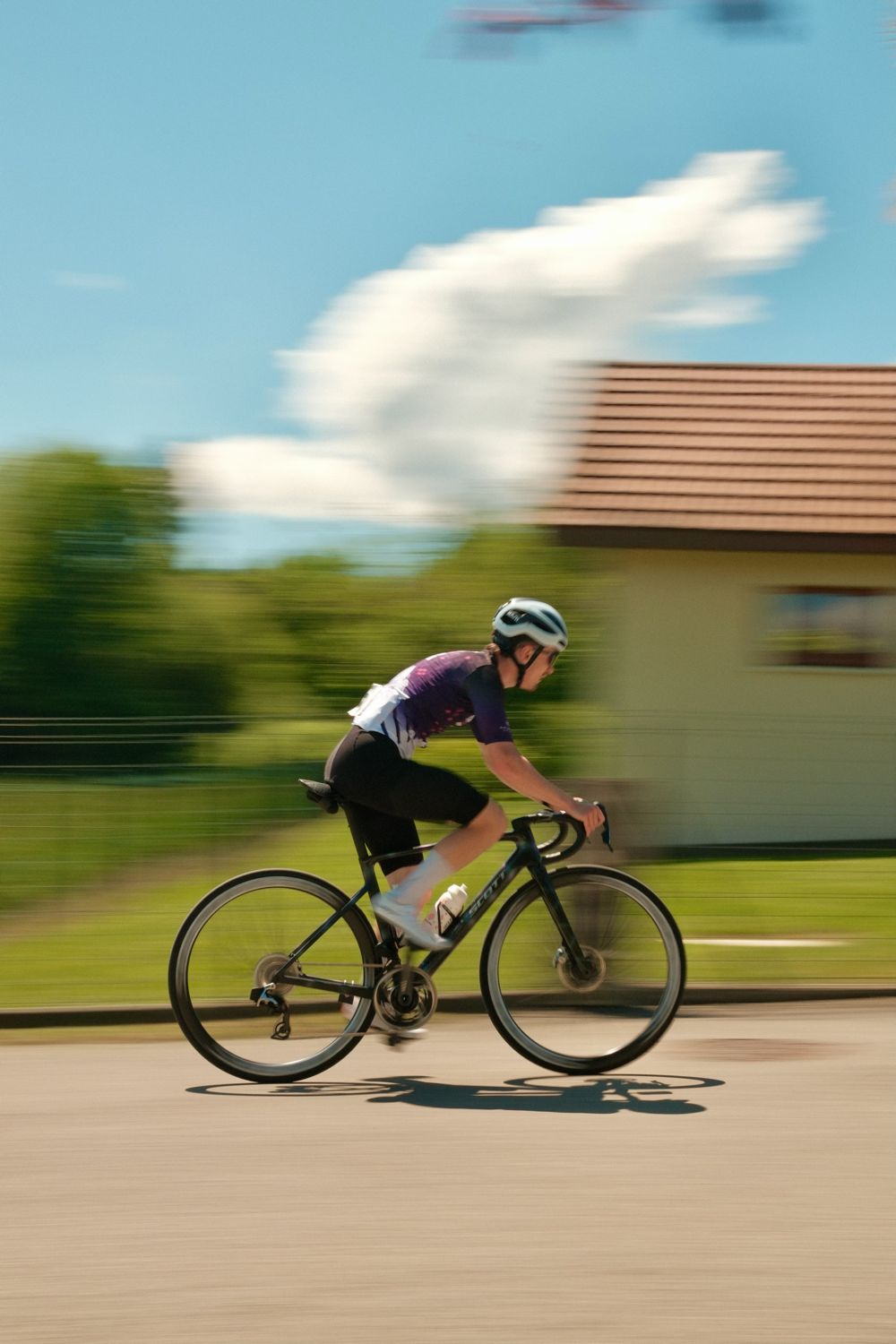 Filé d'un cycliste en maillot violet sur une route ensoleillée