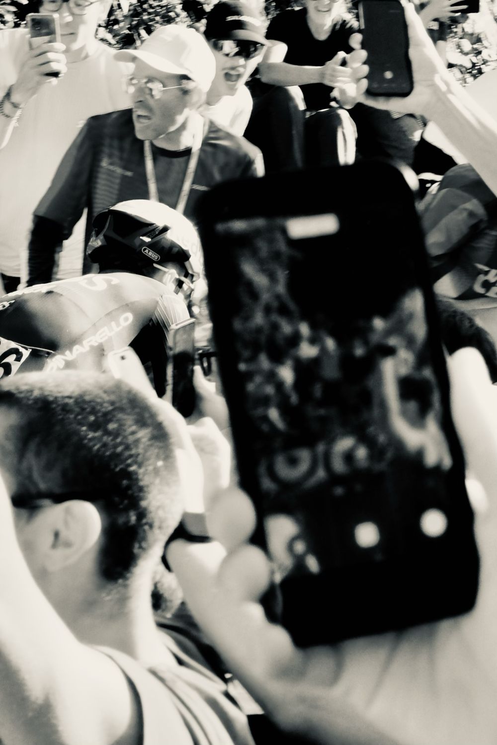 Spectateur filmant la course avec son smartphone, en noir et blanc