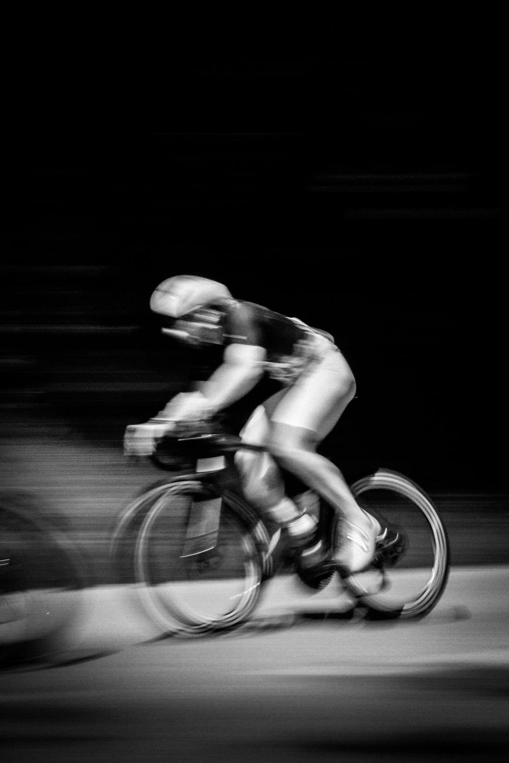 Filé d'un cycliste sur fond noir, en noir et blanc